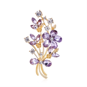 Elegant gold flower brooch with purple crystal petals and rhinestones on white background