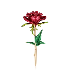 Élégante broche rose vintage avec pétales en émail rouge et feuilles vertes sur fond blanc
