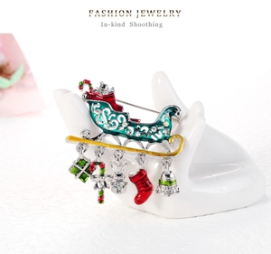 Detail view of a Christmas sled brooch with rhinestones and five festive charms