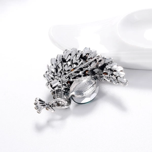 Broche paon vintage en argent avec cristaux ambrés et verts sur céramique blanche