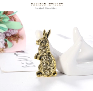 Close-up of vintage golden rabbit brooch featuring detailed fur texture on ceramic hand