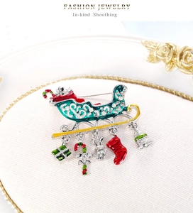 Detail of Christmas sleigh brooch with green enamel, rhinestones and five festive charms