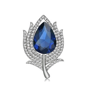 Macro shot of silver leaf brooch with blue teardrop crystal and pave crystal details