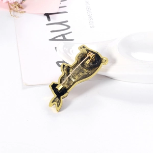 Back view of vintage rabbit brooch in antique gold alloy with bow detail on white plate
