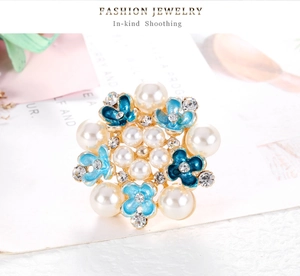 Detalle macro del broche de flor azul con perlas incrustadas y diamantes de imitación