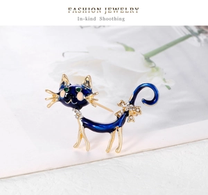 Détail de la broche chat en émail bleu avec yeux verts en gemme et nœud en cristaux