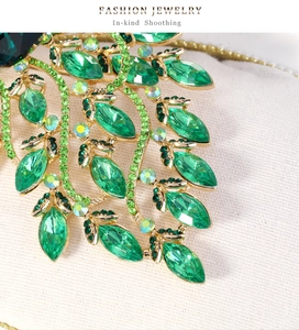 Macro shot of green marquise-cut gems and rhinestones on a gold-plated peacock brooch