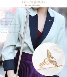 Detailed close-up of golden Caduceus medical wing brooch with sparkling rhinestones