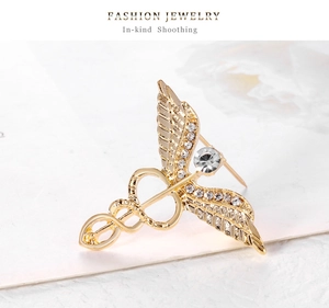 Close-up of golden caduceus brooch with sparkling rhinestones on angel wings