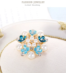 Detalle macro de broche de flor en esmalte azul con perlas y strass sobre base dorada
