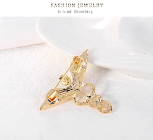 Macro view of gold angel wing brooch back showing safety pin clasp and hollow structure