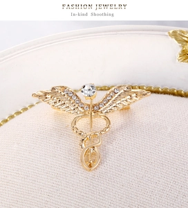 Detailed macro view of gold-plated Caduceus wing brooch with white rhinestones