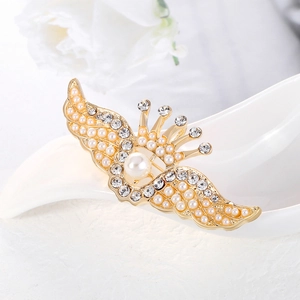 Élégante broche ailes couronne dorée avec perles et strass sur un support blanc pur