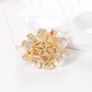 Elegante broche de flor dorada con perlas blancas y detallada artesanía en metal fino