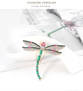 Detailed macro view of dragonfly brooch with green crystals and sparkling diamonds