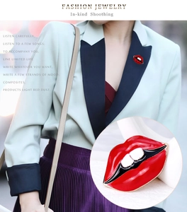 Détail d'une broche lèvres en émail rouge avec bords dorés sur un blazer vert pour femme