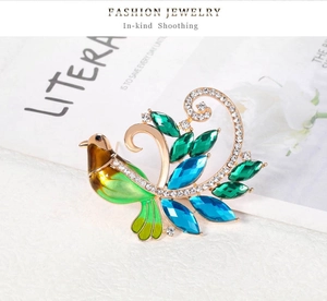 Détail macro d'une élégante broche paon en cristal vert avec perles et strass sur or