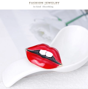 Détail d'une broche lèvres rouges émaillées posée dans une cuillère en porcelaine