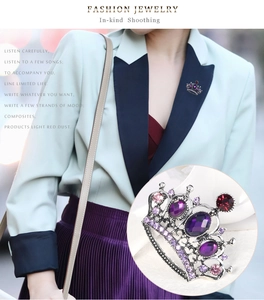 Macro shot of crown brooch featuring purple oval stone and silver alloy setting on a model