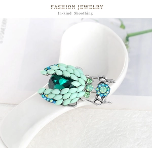 Detailed close-up of emerald beetle brooch with green crystals in a ceramic spoon