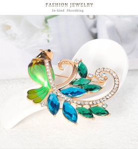 Détail macro de broche oiseau en émail vert avec cristaux et perles sur une cuillère