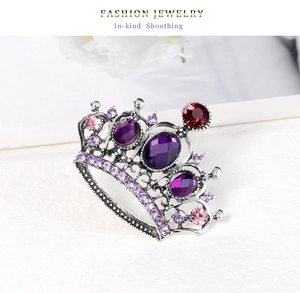Close-up of vintage silver crown brooch with purple oval gemstone and floral background