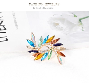 Vue détaillée d'une broche spirale en cristal coloré avec base dorée et strass
