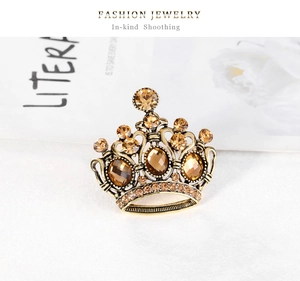 Dettaglio spilla a corona vintage in oro con cristalli ambra champagne e strass lucenti