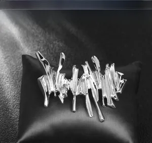 Macro view of irregular silver liquid metal brooch with mirror finish on black leather