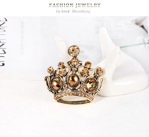 Dettaglio della spilla a corona vintage in bronzo con strass ambrati su modello di mano