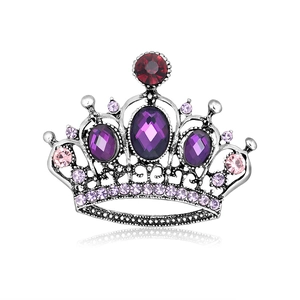 Broche couronne vintage en argent avec strass violets et rouges sur fond blanc
