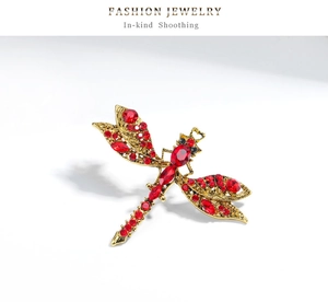 Macro shot of vintage dragonfly brooch with red rhinestones and golden filigree wings