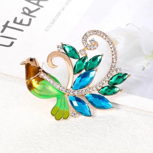 Élégante broche phénix verte avec cristaux colorés et perles sur une base dorée
