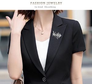 Close-up of irregular silver metal brooch styled on a professional black blazer lapel