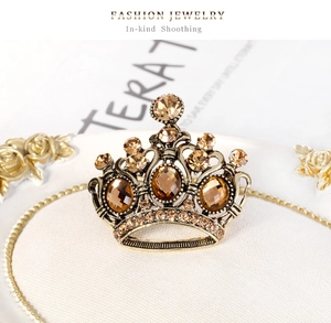 Dettaglio macro di spilla a corona vintage con cristalli ambra e strass in oro antico