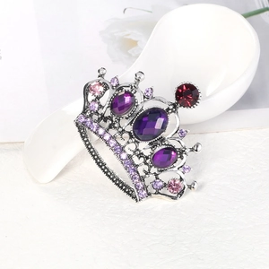 Elegant silver crown brooch featuring purple and pink crystals on white ceramic background