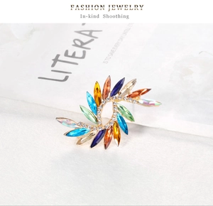 Détail d'une broche en cristal multicolore avec monture dorée en spirale et strass fins