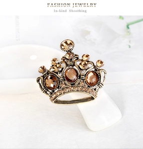 Dettaglio ravvicinato di una spilla a corona dorata vintage con strass e cristalli champagne