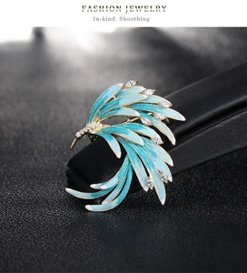 Detailed close-up of a phoenix brooch featuring blue enamel and sparkling cubic zirconia
