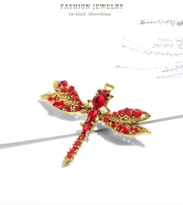 Detailed close-up of a vintage dragonfly brooch with red rhinestones and gold alloy wings