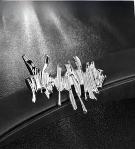 Detailed close-up of liquid metal style irregular silver brooch on black leather texture