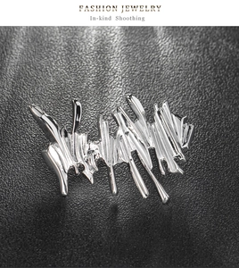 Detail of silver irregular liquid metal brooch on black leather background