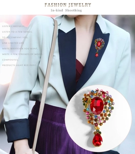 Détail macro d'une broche vintage de luxe avec pendentif goutte rouge et cristaux colorés