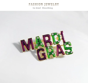 Close-up of Mardi Gras letter brooch with purple green enamel and sparkling rhinestones