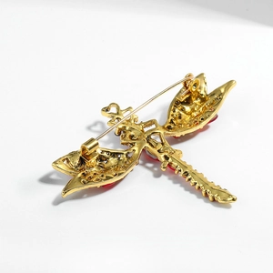 Vintage gold-plated dragonfly brooch with red rhinestones on a clean white background