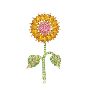 Exquisite sunflower brooch with yellow crystals and green leaves on a white background