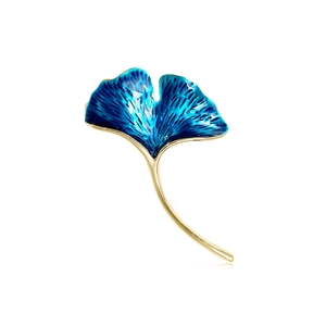 Detailed macro view of ginkgo leaf brooch featuring blue enamel and golden metallic edges