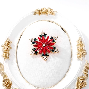 Détail de la broche flocon de Noël avec cristaux rouges et émail vert sur métal doré