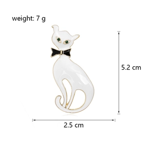 Broche chat blanc mignonne avec nœud noir et yeux en pierres vertes sur blanc