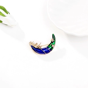 Macro detail of crescent moon brooch with blue enamel inlay and gold castle details